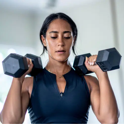 Woman lifting weights to ease perimenopause symptoms.